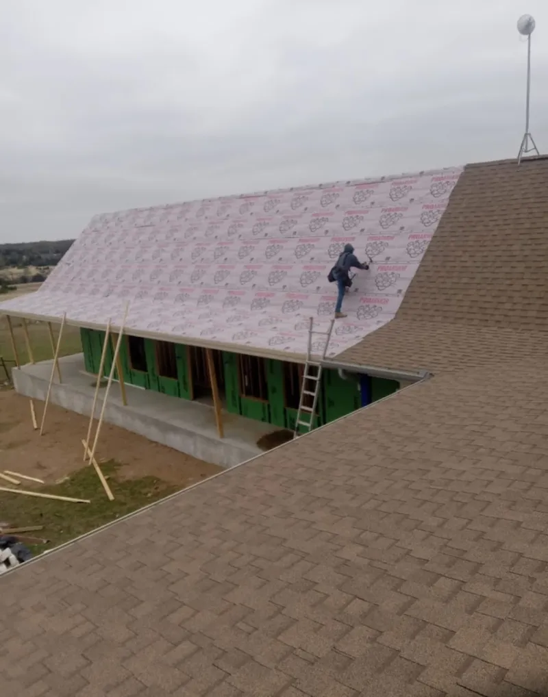 Worker preparing underlayment for a metal roof installation in Glenwood